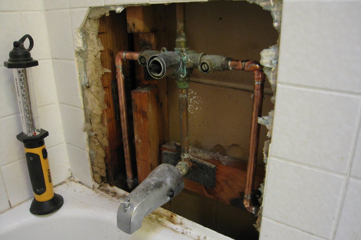 Rough-in pipe repair opened behind a bathroom wall